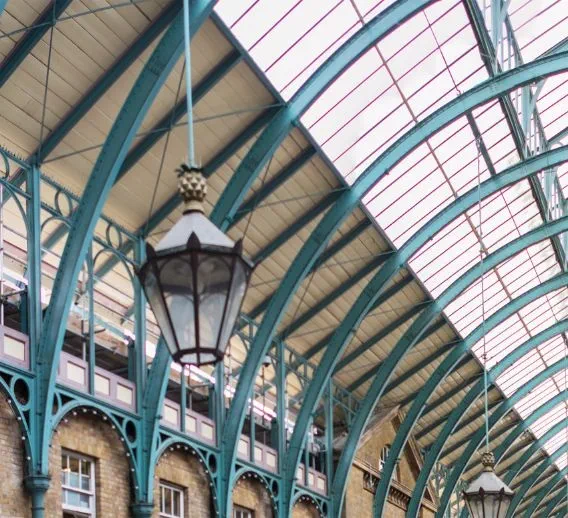 An arched ceiling with rows of teal supports and traditional style pendant lights