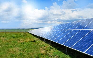 An angled view of solar panels in an open field on a sunny day